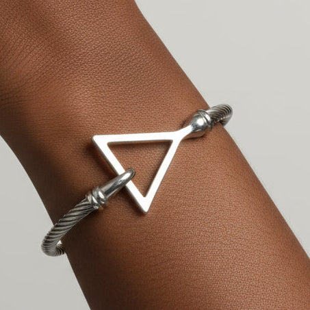 A silver cable-style cuff bracelet with a large open Delta charm.